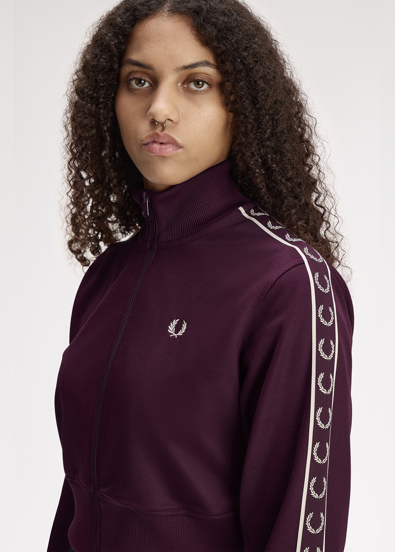 A female model wearing a Fred Perry Cropped Taped Track Jacket in Plum