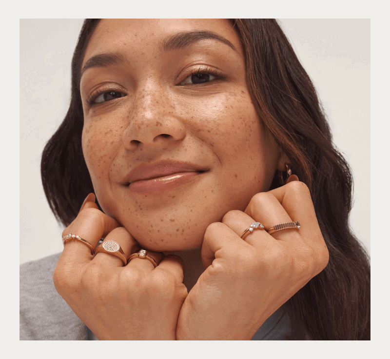 Woman wearing an assortment of yellow gold rings and pair of earrings.