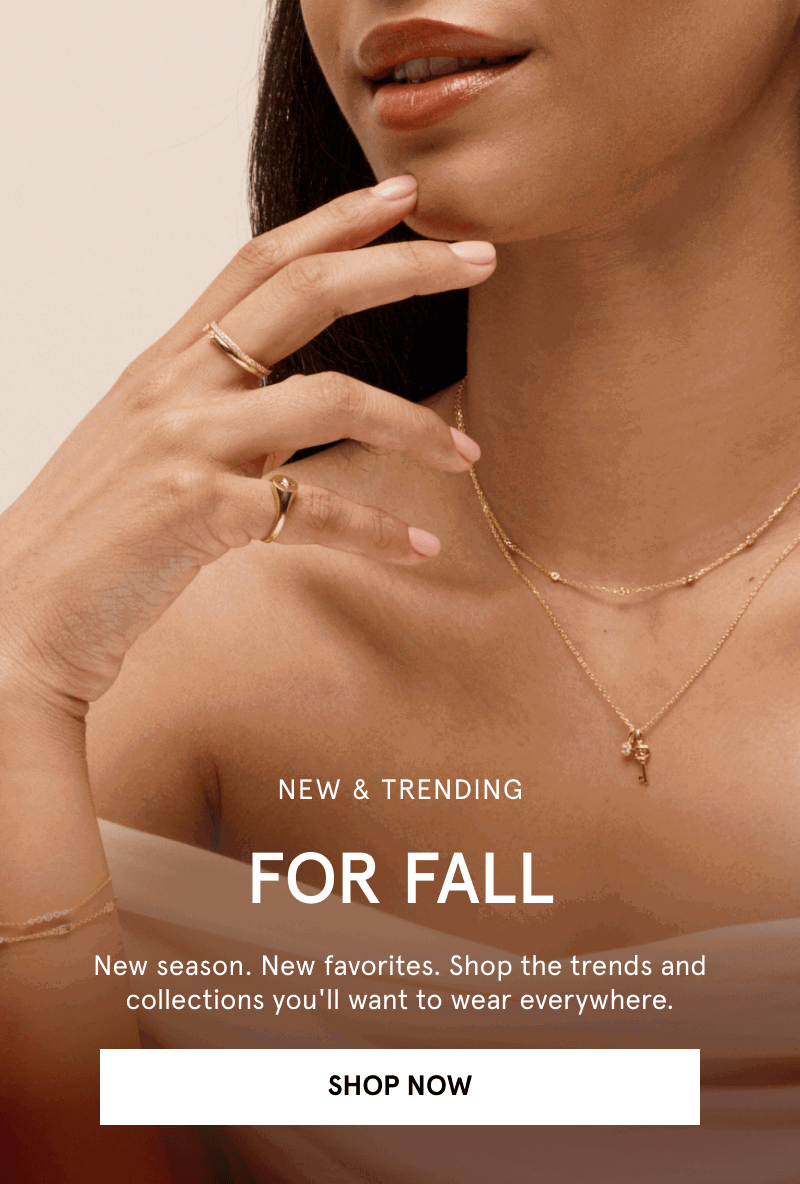 Closeup of woman wearing delicate layered yellow gold necklaces and gold rings. Now and trending for fall. Click shop now.