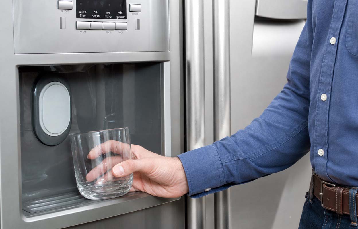 A man getting water from the fridge