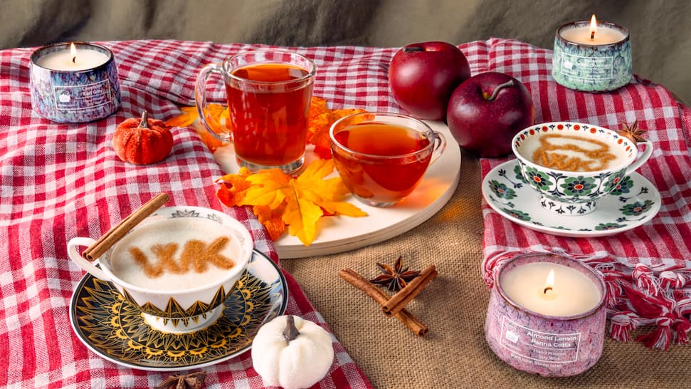 Hot tea lattes surrounded by candles, fall leaves, apples and pumpkins