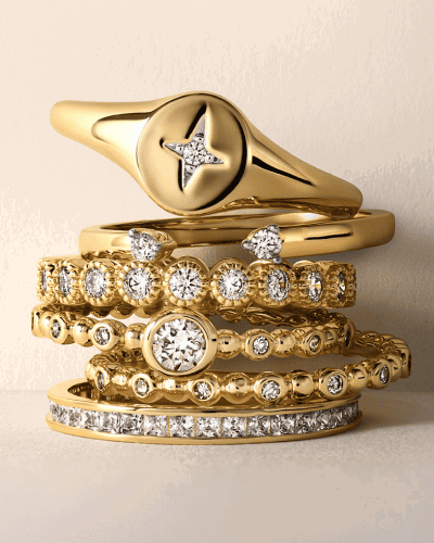 Stacked yellow gold rings and bands with diamond accents.