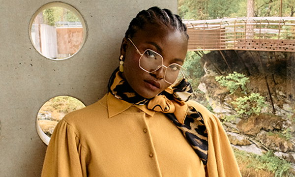 Woman wearing a scarf, gold earrings and glasses.
