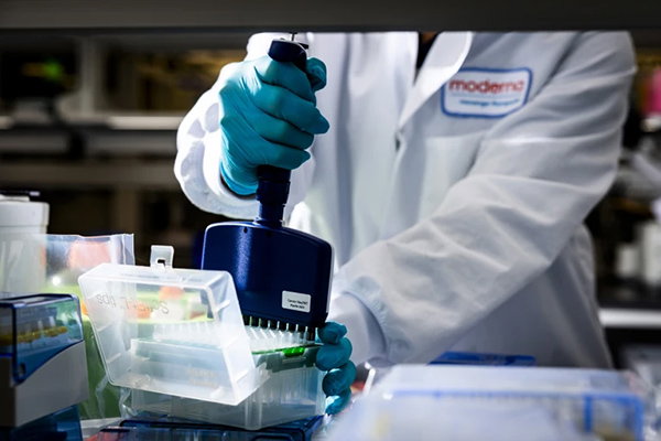A photograph of a scientist at Moderna working in a lab.