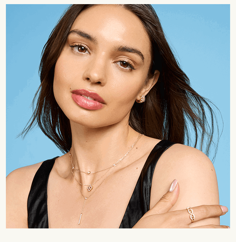 Model in layered dainty gold necklaces with delicate diamond details. 