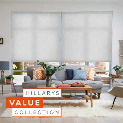 Bright living room with two large windows dressed in light patterned Roller blinds behind a grey sofa and wooden coffee table.