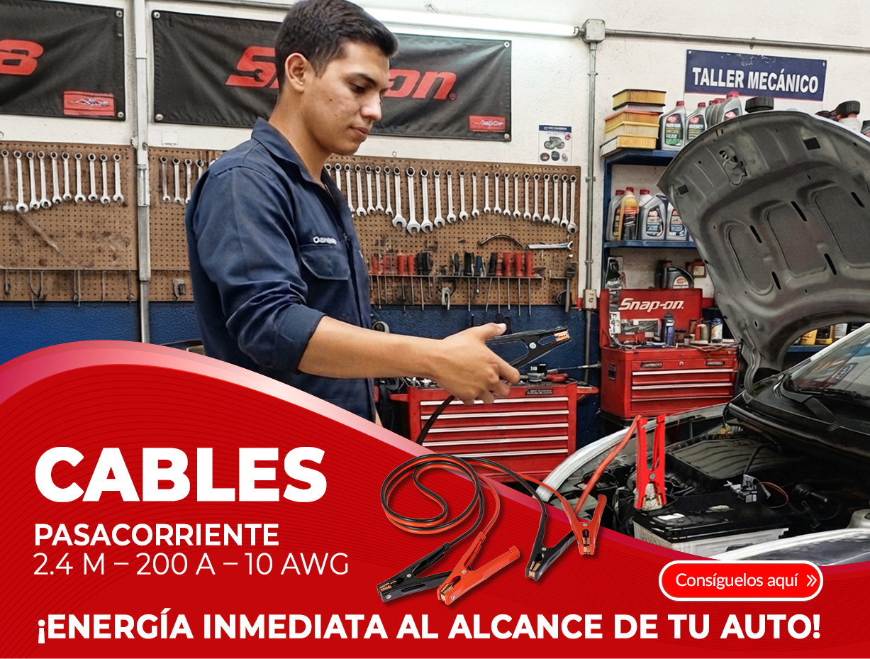 Mechanic in garage connecting jumper cables to a car battery with open bonnet and workshop tools in the background