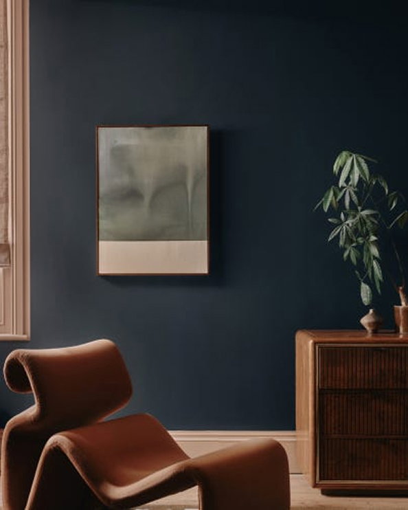 Stylish room with deep blue walls, brown chair, and framed artwork.