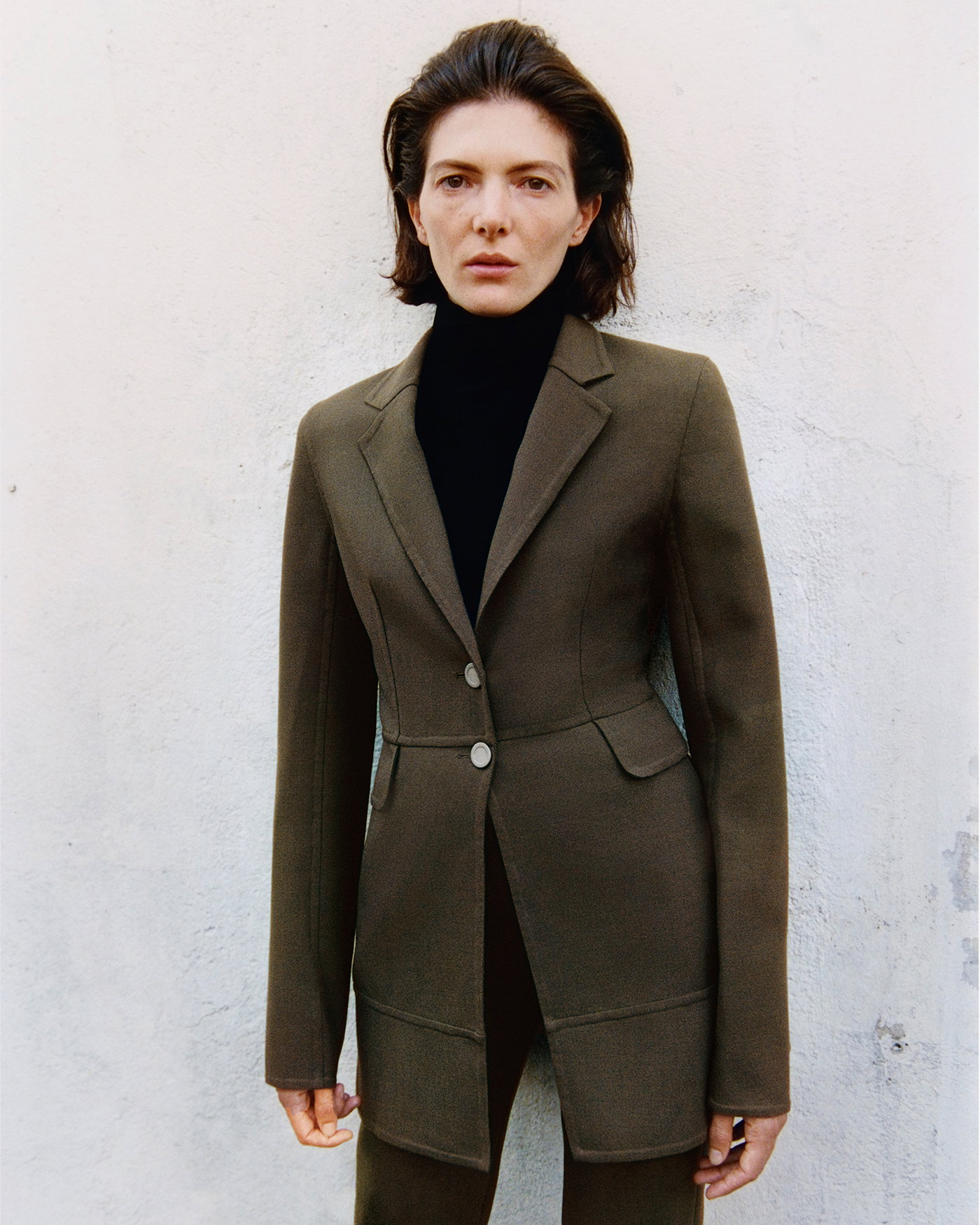 Campaign Image of model standing against a cement wall wearing the 