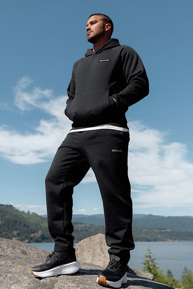 A man in a black sweat set standing outside.