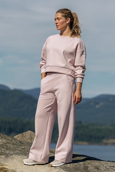 A woman wearing a light pink sweat set, standing outside.