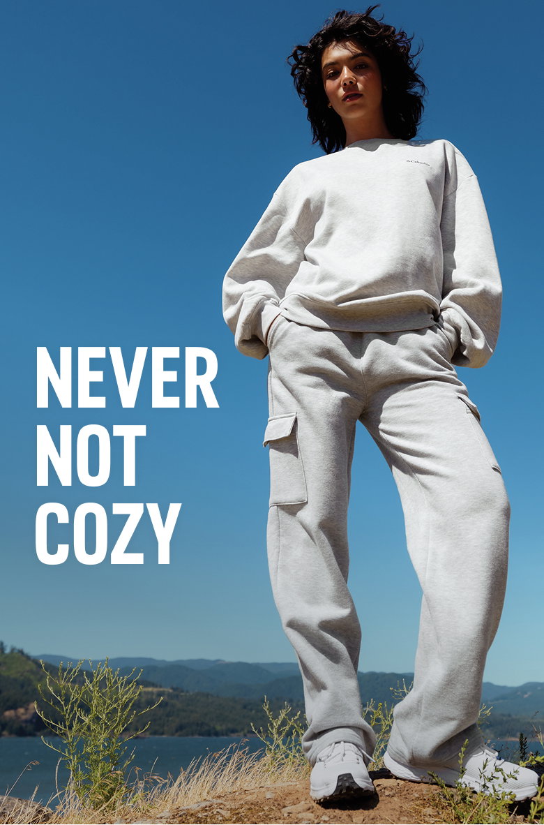 A woman model in a gray sweat set with text: NEVER NOT COZY