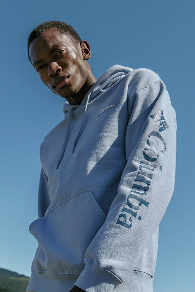 A man wearing a light blue hoodie against a blue sky.