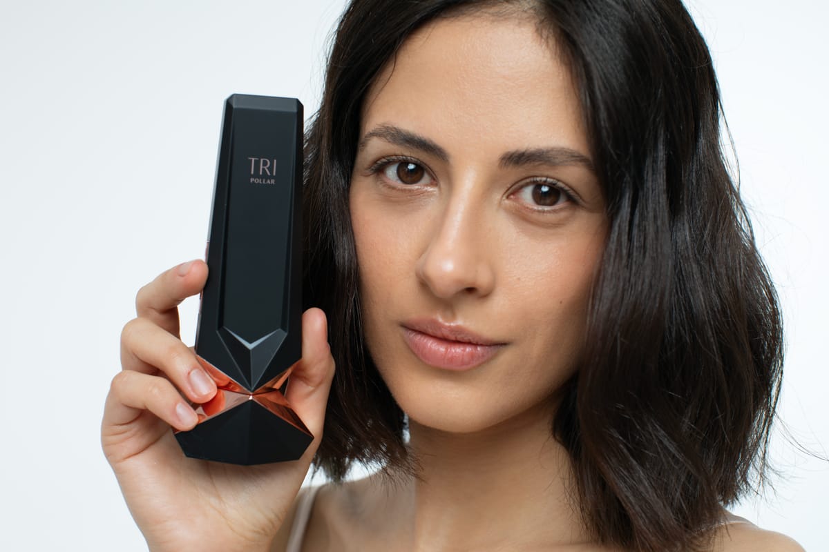 Woman holding the TriPollar STOP Vx 2 device beside her face