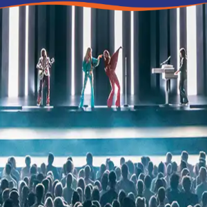A live music performance featuring four musicians on stage with bright lights and an engaged audience.
