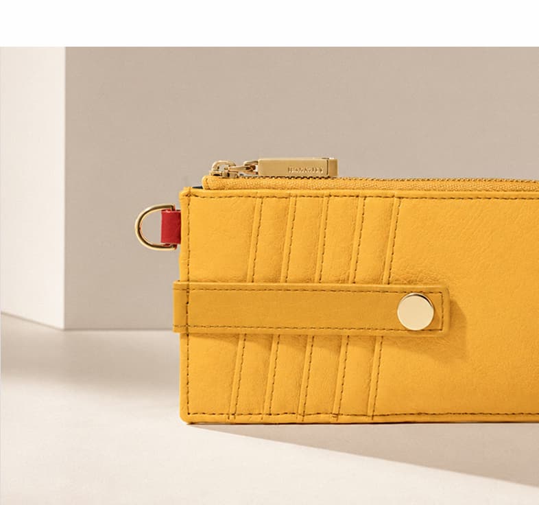 Close-up of a Double Yellow leather zip 210 East wallet with card slots, gold hardware, and a red accent tab.