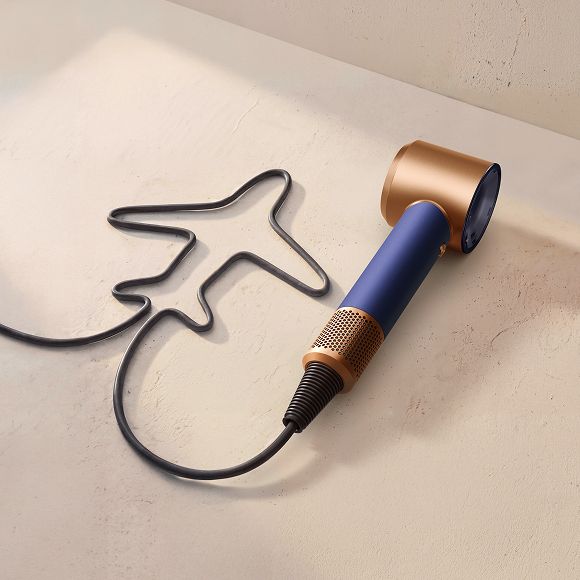 Dyson Supersonic Travel hair dryer with the cable shaped to resemble an aeroplane.
