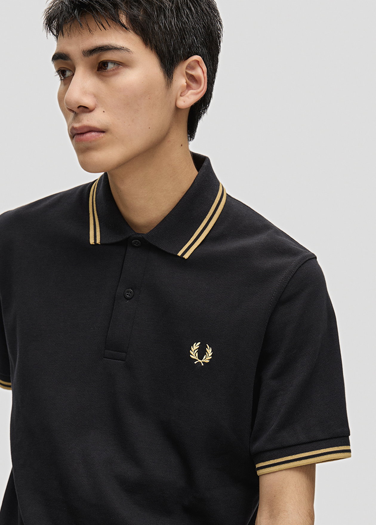 Male model wears an M12 Fred Perry Shirt in Black / Champagne / Champagne