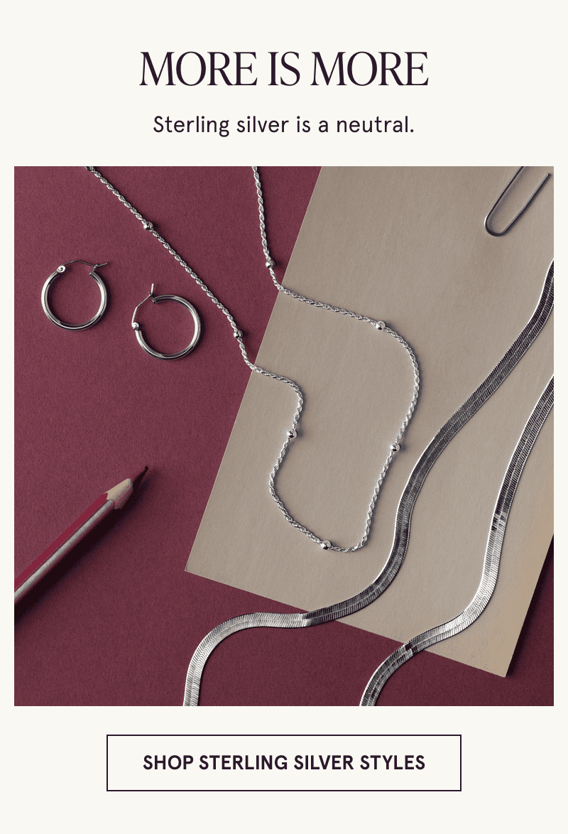 A pair of hoops and 2 necklaces on paper next to a colored pencil. More is more. Click to shop sterling silver styles
