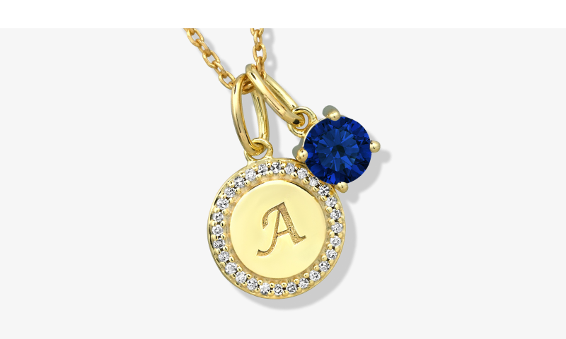 Yellow gold initial pendant necklace with diamond halo and blue sapphire charm.
