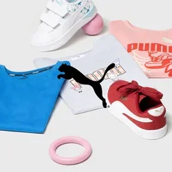 Puma-Bekleidung, darunter blaue und rosa T-Shirts, weiße und rote Turnschuhe, ein rosa Ring und zwei Bälle. Auf einem neutralen Hintergrund.