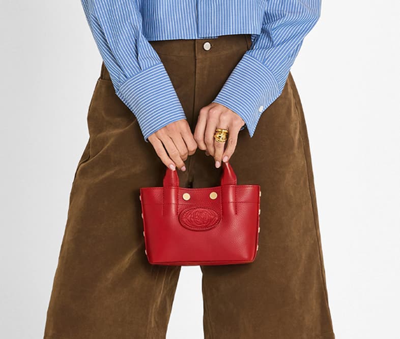 Model in a brown suede jacket carrying a small Double Yellow Olympia with top handles and gold hardware.
