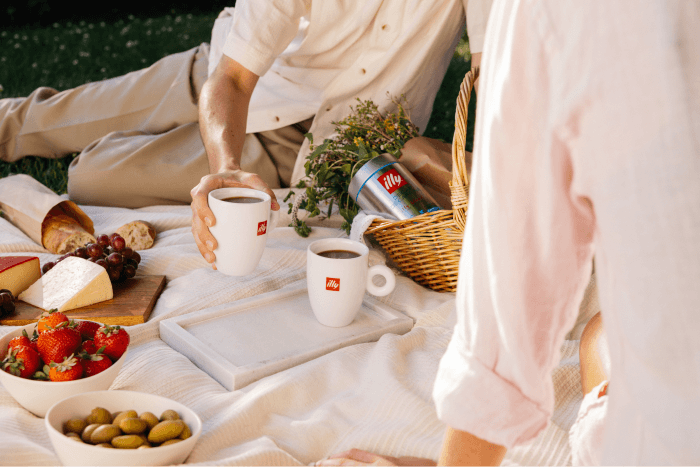 Illy coffee cups and a picnic spread of fruit, cheese, bread, and olives