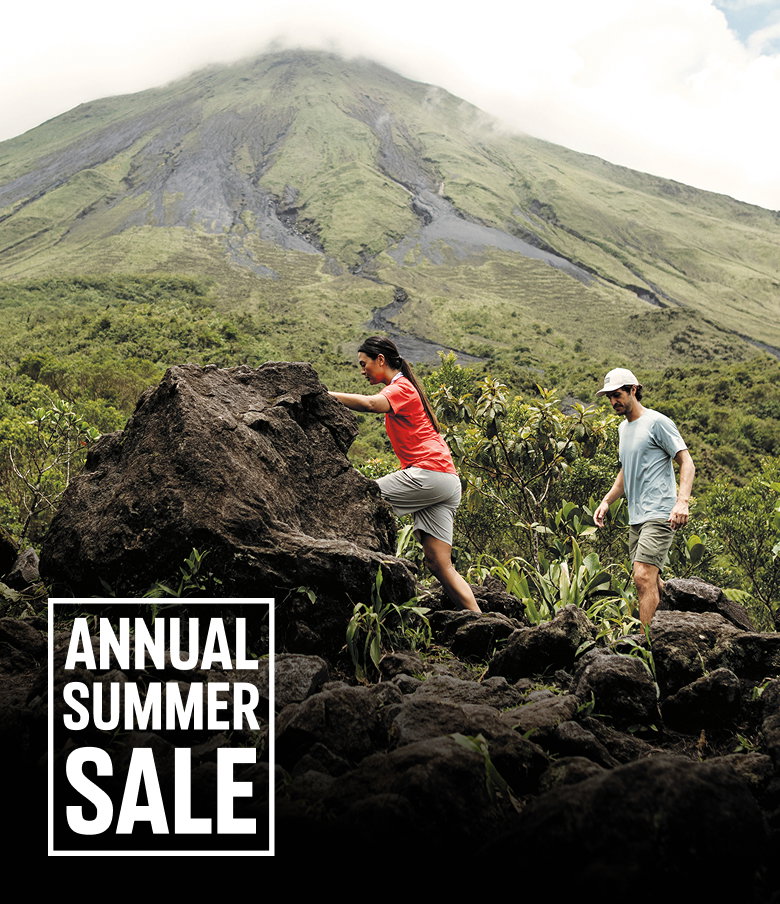 Two hikers exploring a volcano trail with text: ANNUAL SUMMER SALE