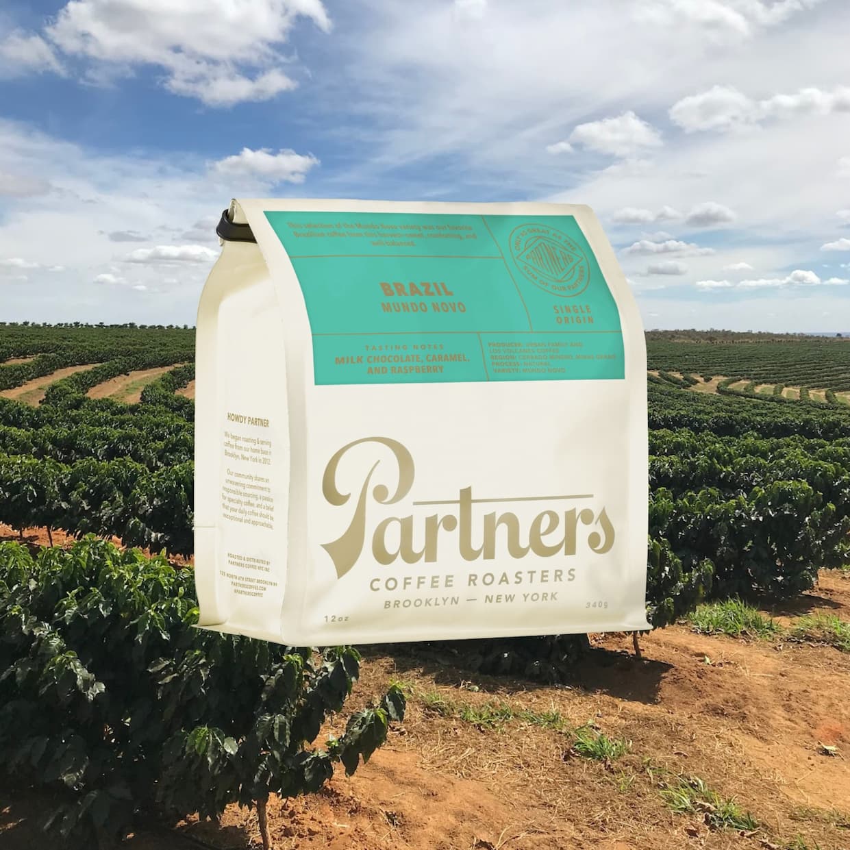 A bag of Partners Coffee Brazil - Mundo Novo over a backdrop of a farm of growing coffee trees.