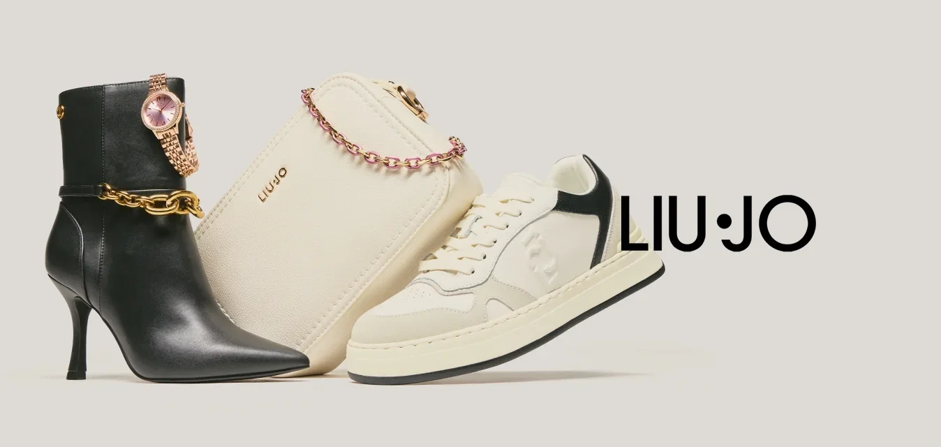 Zwarte enkellaars met hoge hak, goudkleurige kettingen en horloge, beige handtas met roze ketting en crèmekleurige sneakers met zwarte accenten.