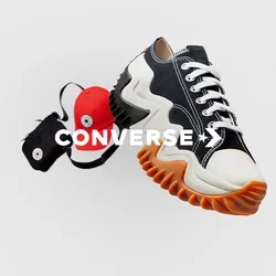Zwart-witte sneaker met zigzagzool en oranje accenten, naast een rode pet en een kleine zwarte tas met een circulair logo.