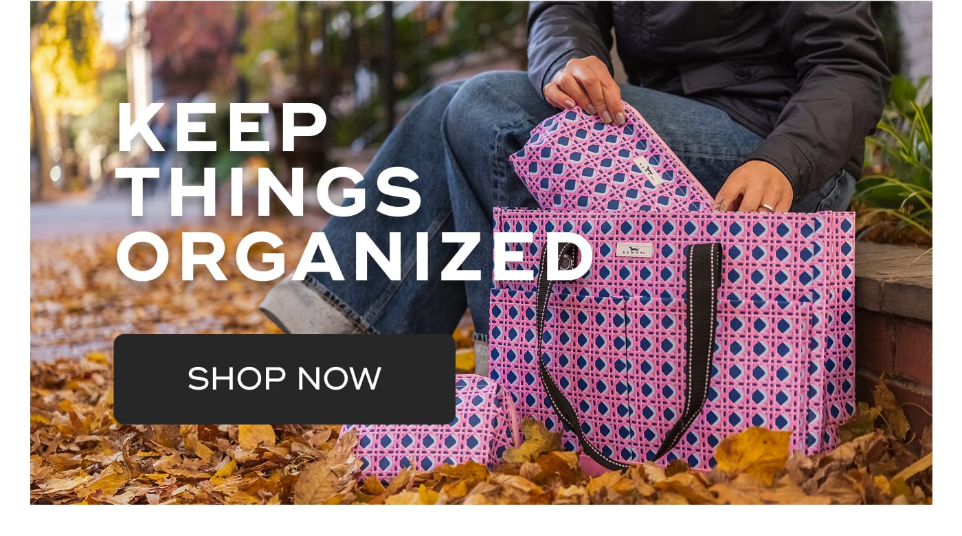 KEEP THINGS ORGANIZED. SHOP NOW. Person sitting on steps with SCOUT bags in a pink and blue geometric pattern.