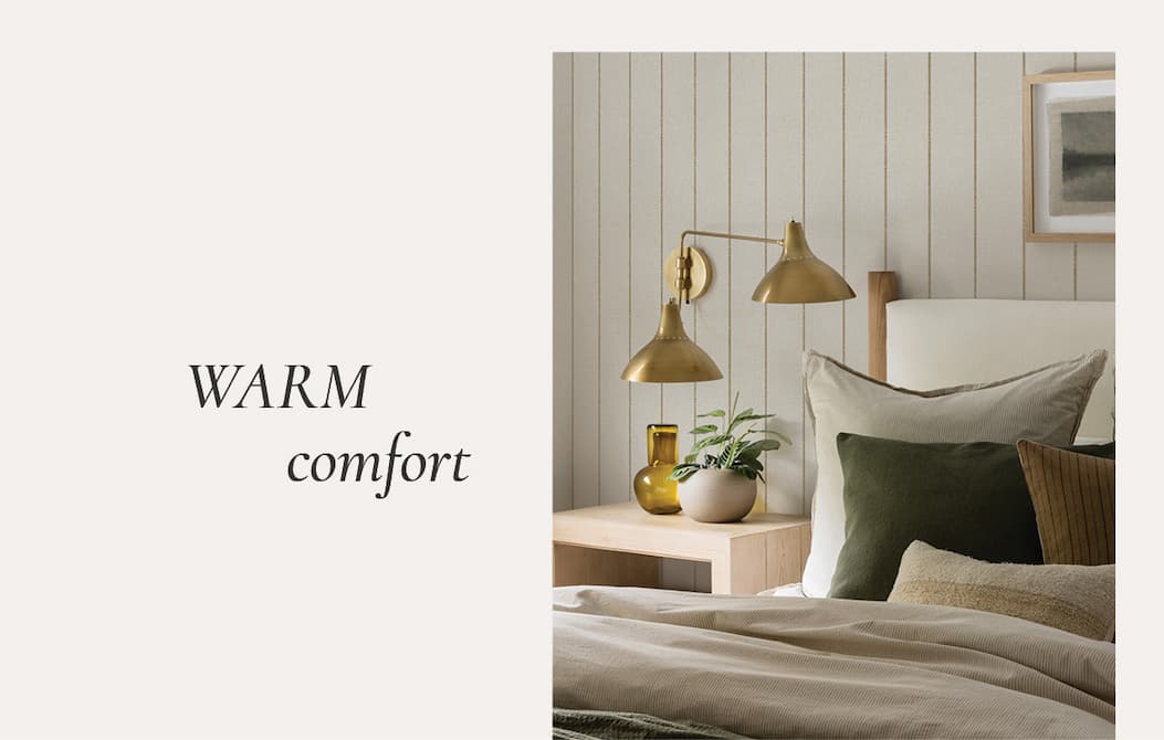 Image of Tempaper's Bursa Stripe wallpaper by Pure Salt installed in a bedroom. Text box "Warm Comfort"