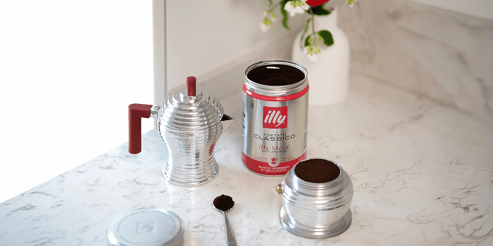 illy Classico coffee with a moka pot and freshly ground coffee on a marble counter