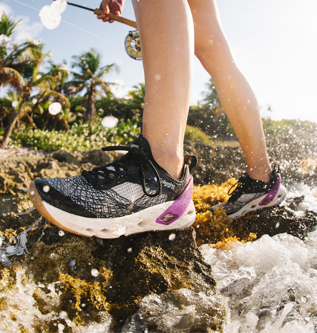 A close up of an angler's no-slip shoes while they are walking on wet rocks. 