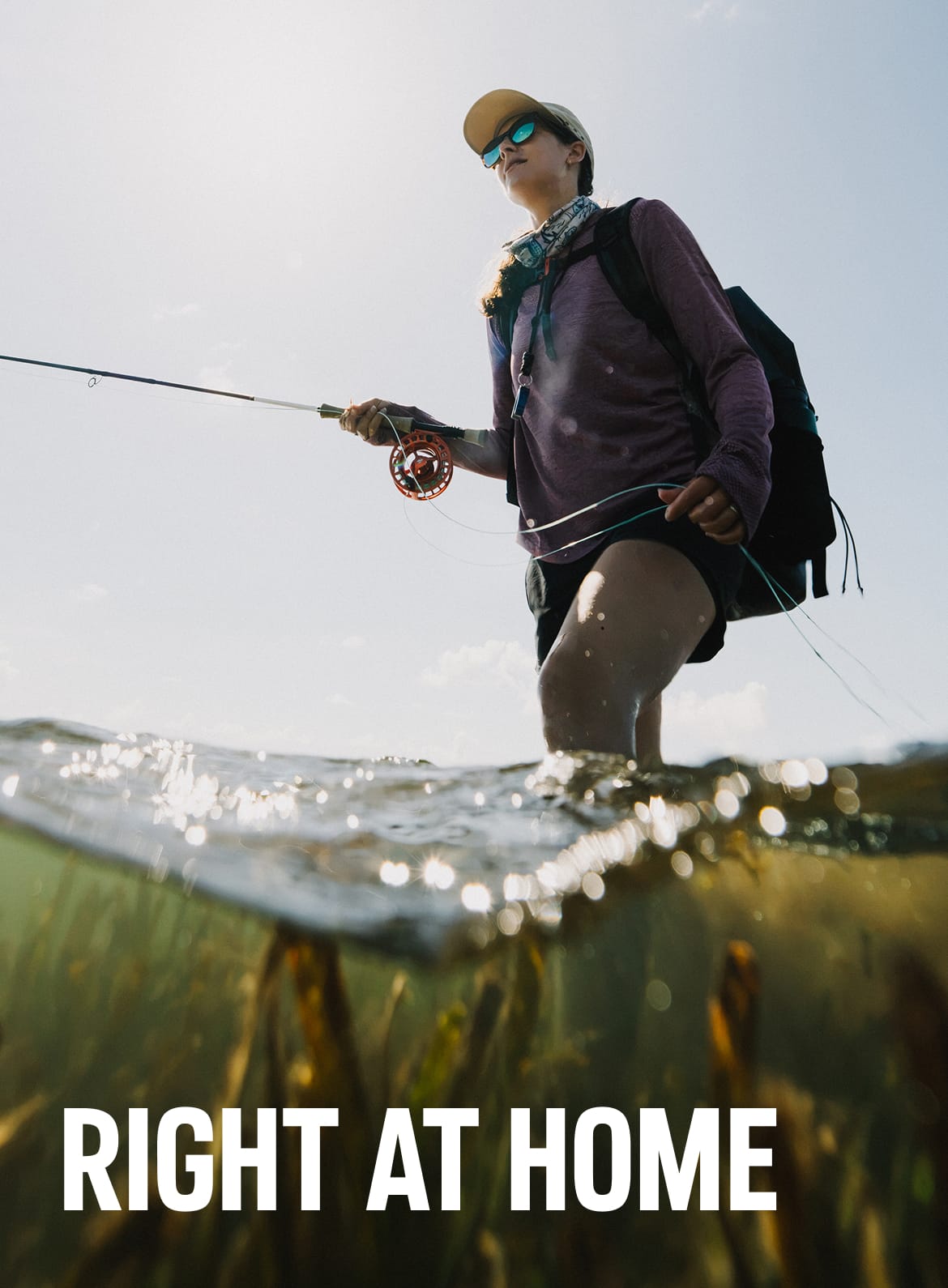 An angler knee deep in green water casting a line. 