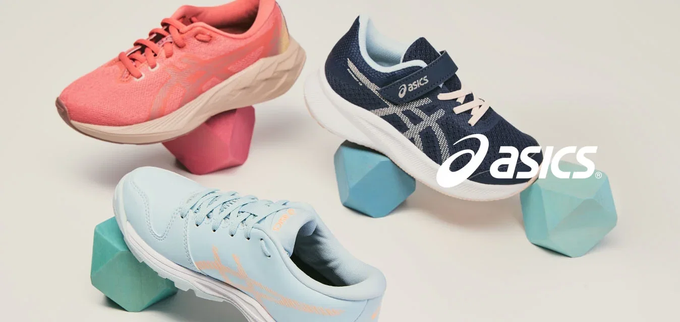 Drie sportschoenen in koraal, marineblauw en lichtblauw in balans op geometrische schuimblokken tegen een effen achtergrond.