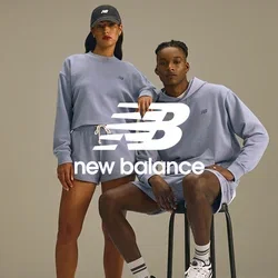 Twee modellen in bijpassende lichtpaarse sportkleding; de ene staat met een pet, de andere zit op een zwarte kruk, beide dragen witte sneakers.