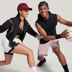 Man en vrouw spelen basketbal, man dribbelt met de bal, vrouw in verdedigende positie, beiden dragen sportkleding en sneakers.
