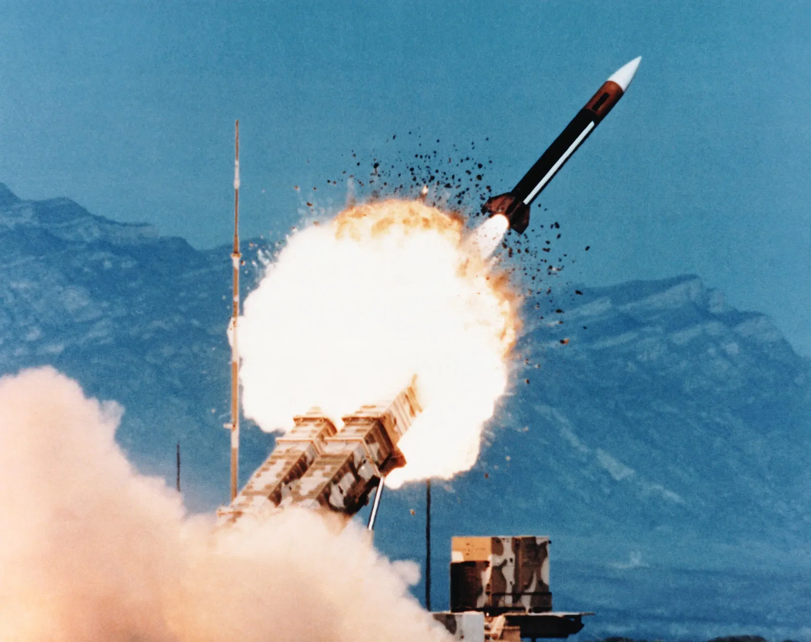 A missile battery is fired, with a mountain range in the background.