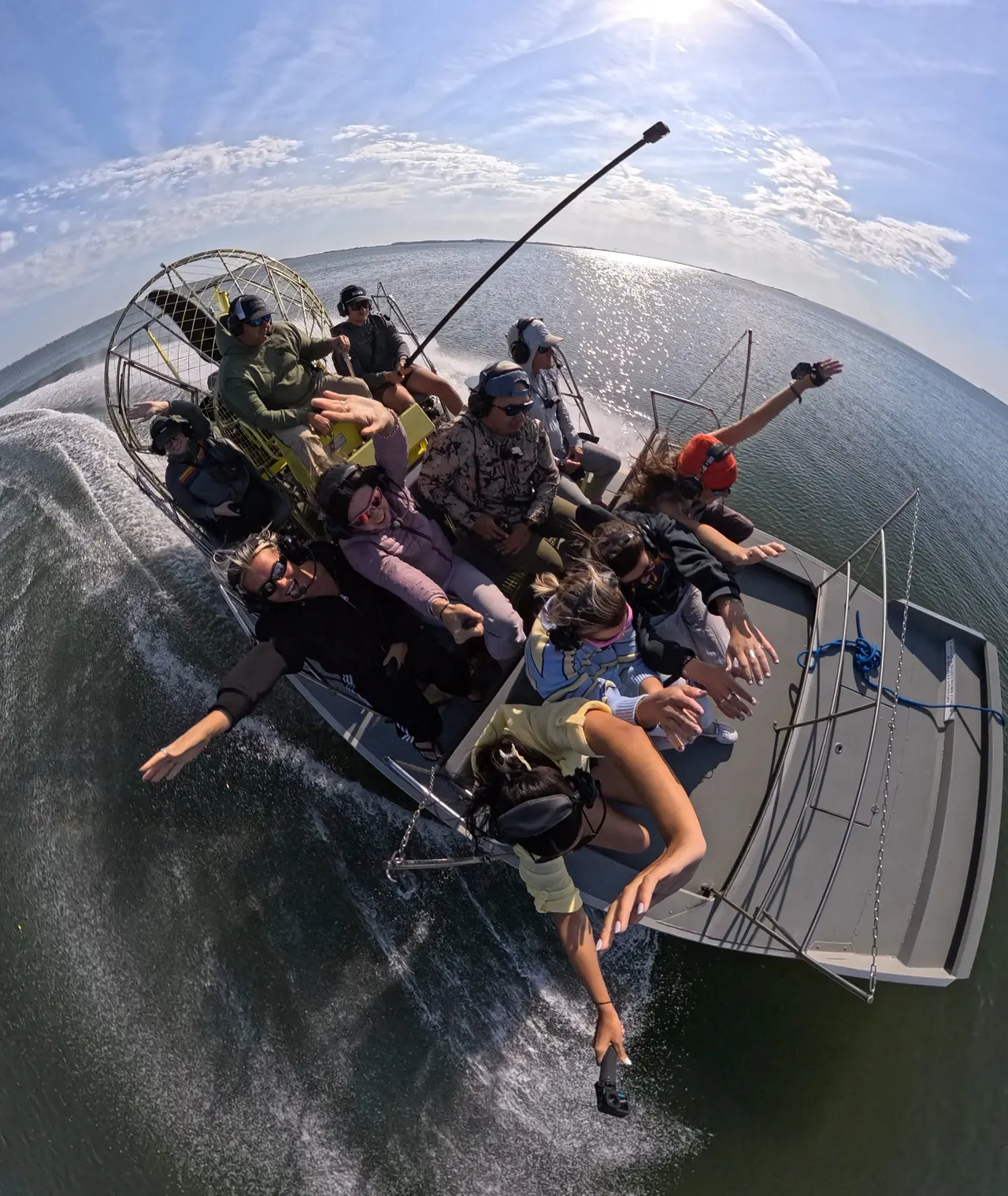 An angler wading in shallow surf holds up a freshly caught fish next to a fly rod and tackle.