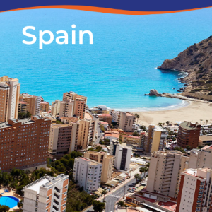 Aerial view of coastal buildings in Spain, with a beach and turquoise sea in the background.