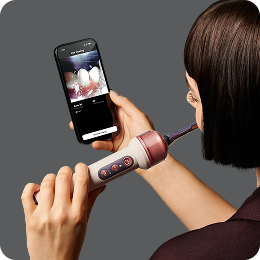 A person uses the MyDyson app and the Dyson CameraJet toothbrush.