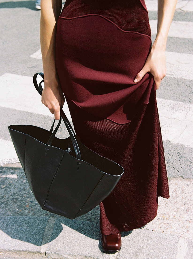 Cropped Campaign image of model wearing the Maissa Dress in Compact Stretch Viscose in Amarone, with the Esme Loafers in Nappa Latex in Umber, Hex Tote in Smooth Calf in Black