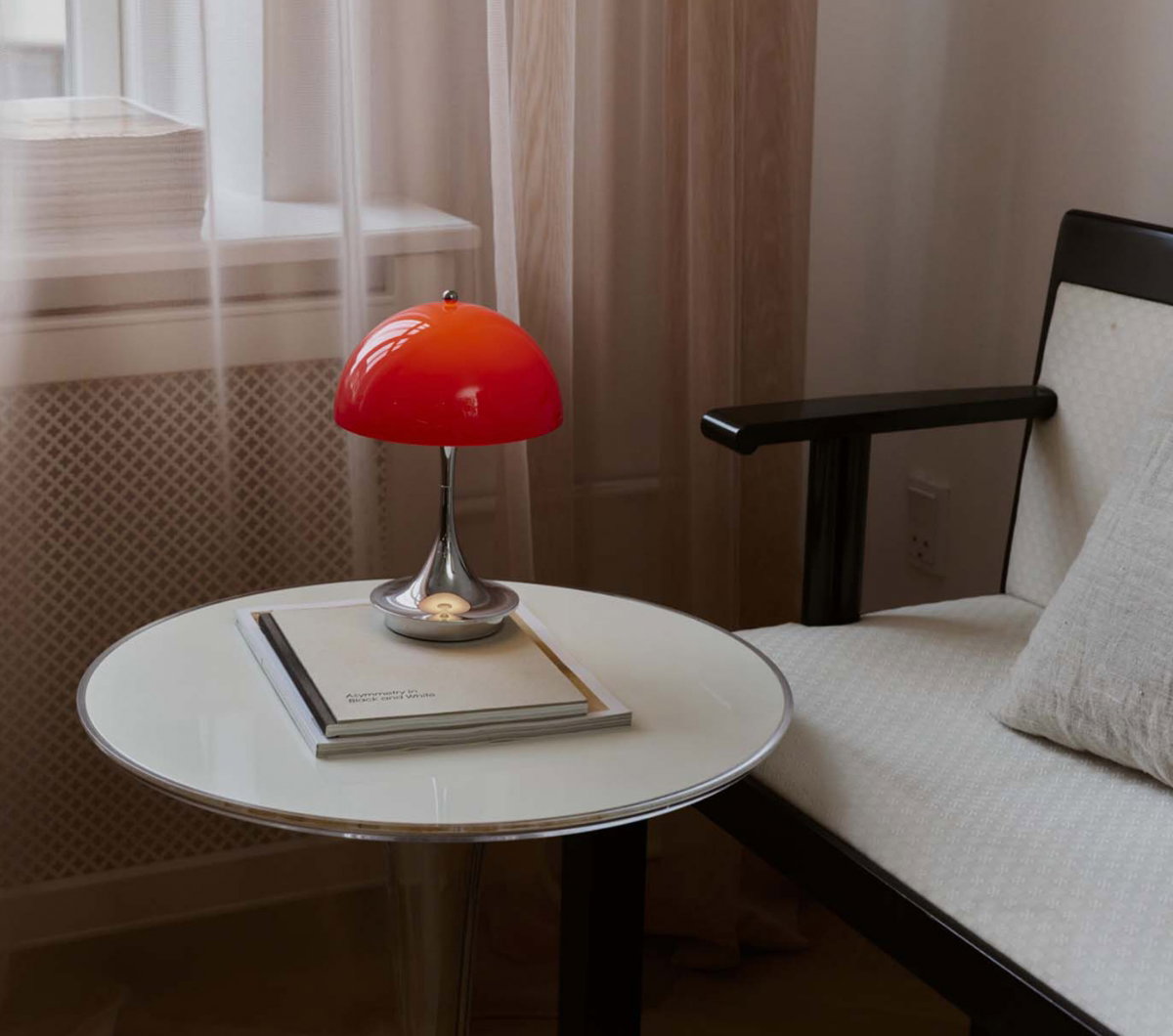 Table lamp with an orange lampshade and a mirror-like metallic base