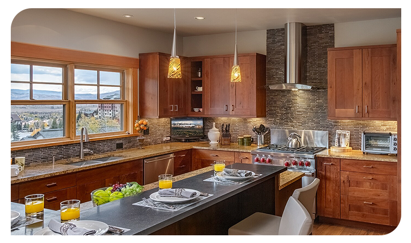 Spacious mountain-view kitchen with wood cabinetry, island seating, and breakfast place settings.