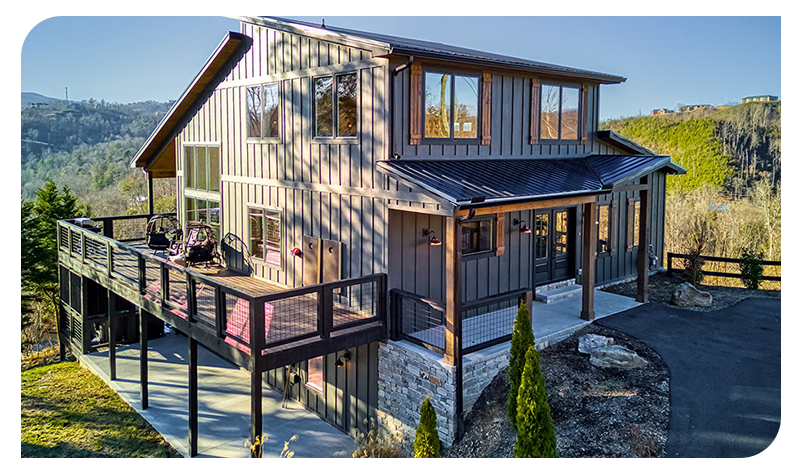Modern mountain cabin with wraparound deck and scenic hillside views.