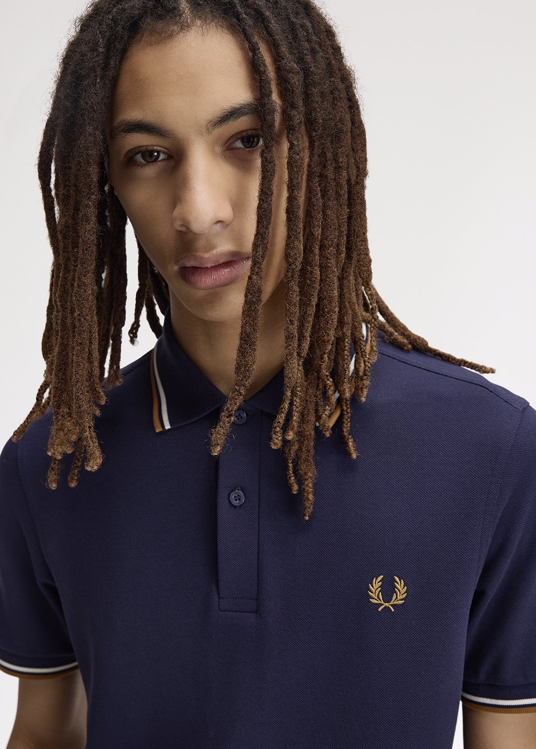 Male model wearing a M3600 Twin Tipped Fred Perry Shirt in Twilight Navy / Snow White / Dark Caramel 