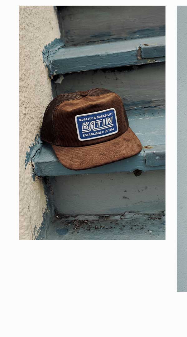 Brown corduroy Katin trucker hat with logo patch resting on a weathered blue staircase
