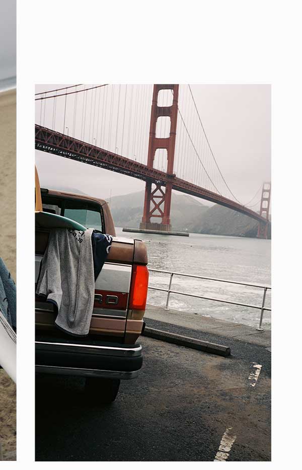 Truck tailgate loaded with a surfboard and towel, Golden Gate Bridge in the background